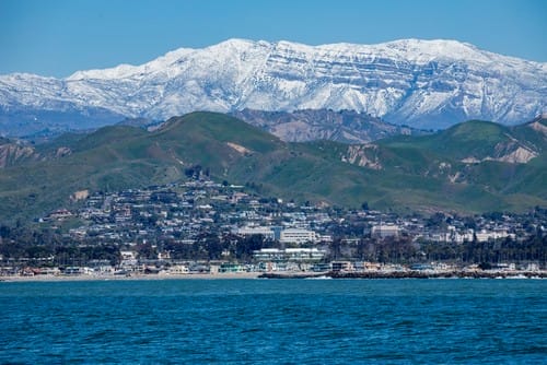 Green Ventura CA Coastline as seen by sea during the winter with snow capped Topatopa Mountains in the background Green Ventura CA Coastline as seen by sea during the winter with snow capped Topatopa Mountains in the background
